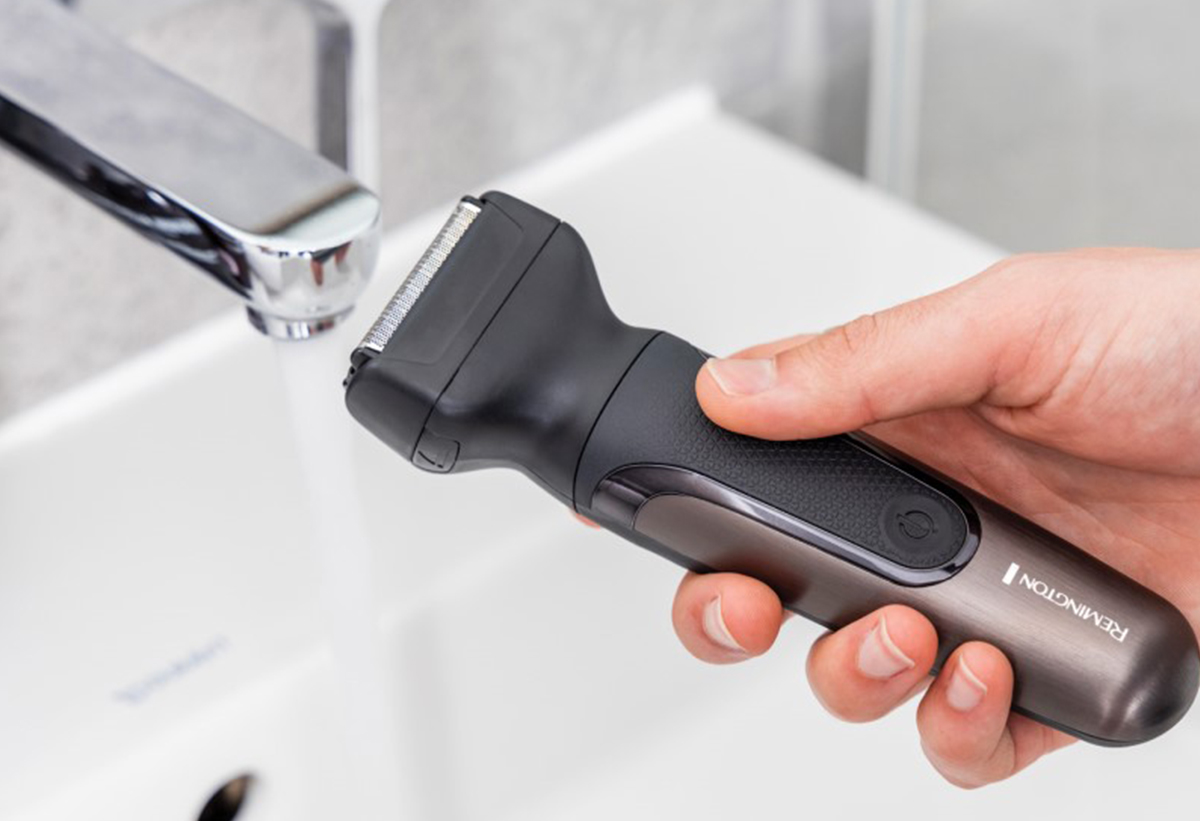 Απεικονίζεται χέρι να κρατάει τη μηχανή δίπλα στη βρύση.